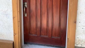 Una puerta de madera con un ventanal en forma de rombo y un teclado electrónico.