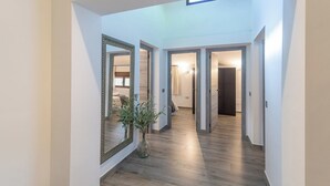 A hallway with a large mirror, a vase with green plants, and wooden flooring. - El Real de Magiaza Riogordo by Ruralidays (Málaga)