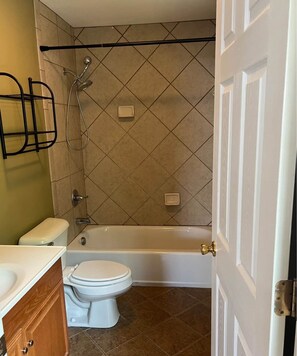 Bathroom features a shower, bathtub, and toilet, with a glass door and towel rack.