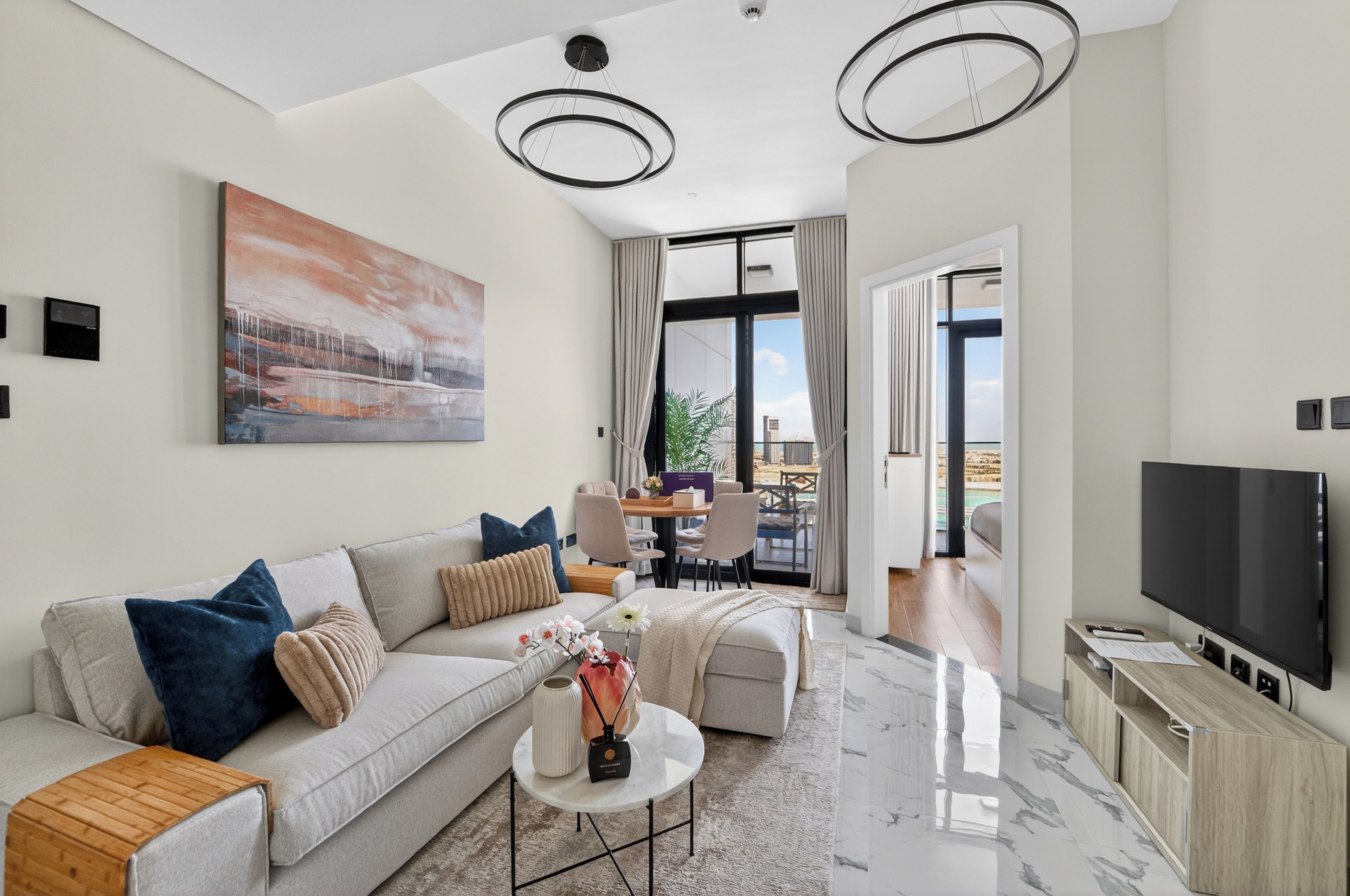 A modern living room with a sofa, coffee table, TV, and artwork.
