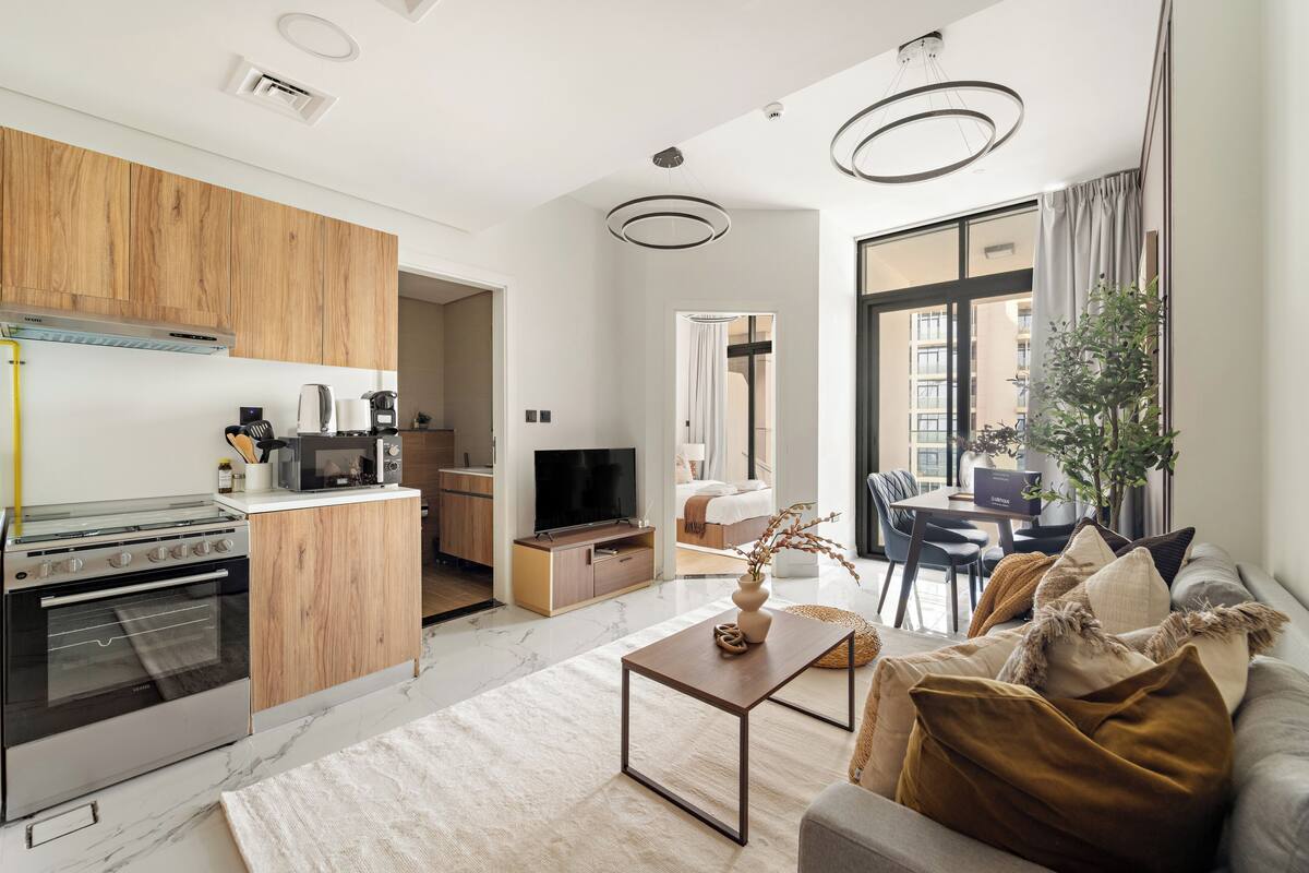 A modern kitchen with wooden cabinets, a built-in oven, and a dining area with a table and chairs.