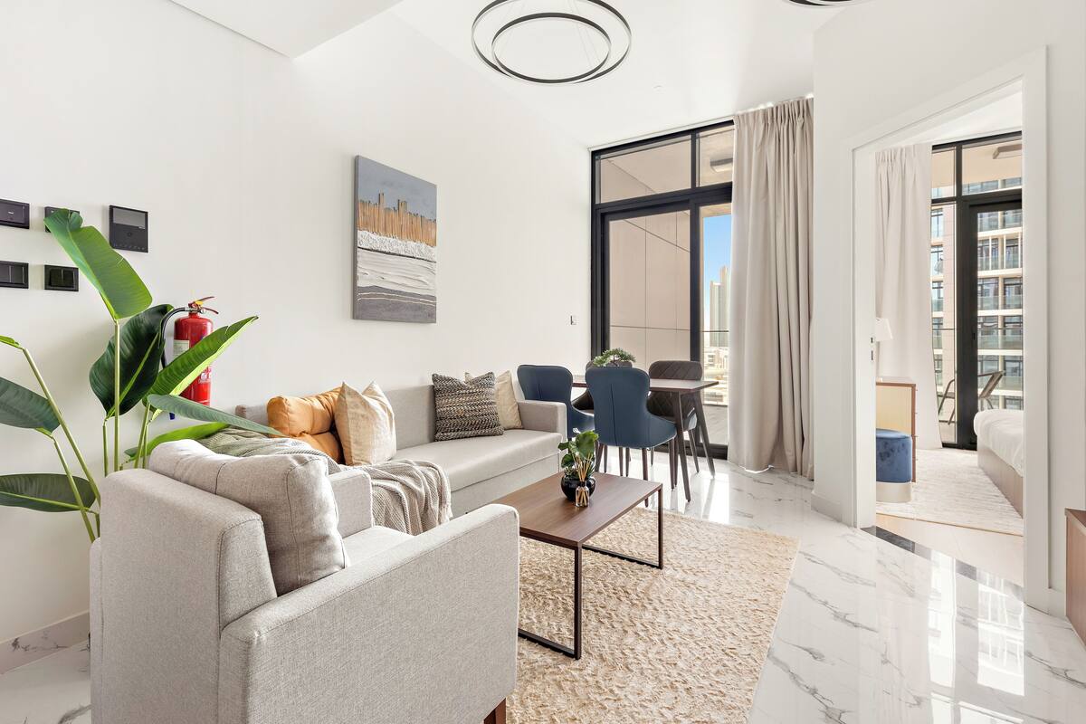 A modern living room with a sofa, coffee table, and large windows.