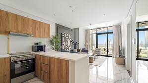 A modern kitchen with wooden cabinets, a built-in oven, and a central island. - Silkhaus Al Maryah Vista 1 (Abu Dhabi)