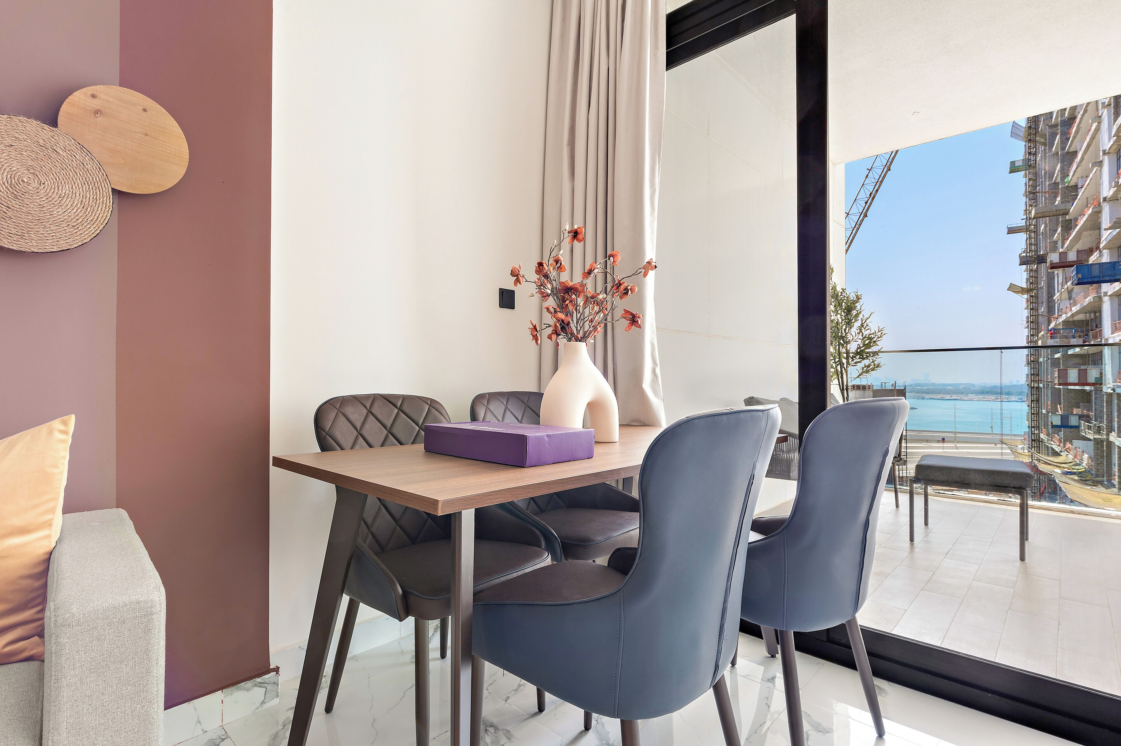 A modern dining area with a table, chairs, and a vase with flowers.