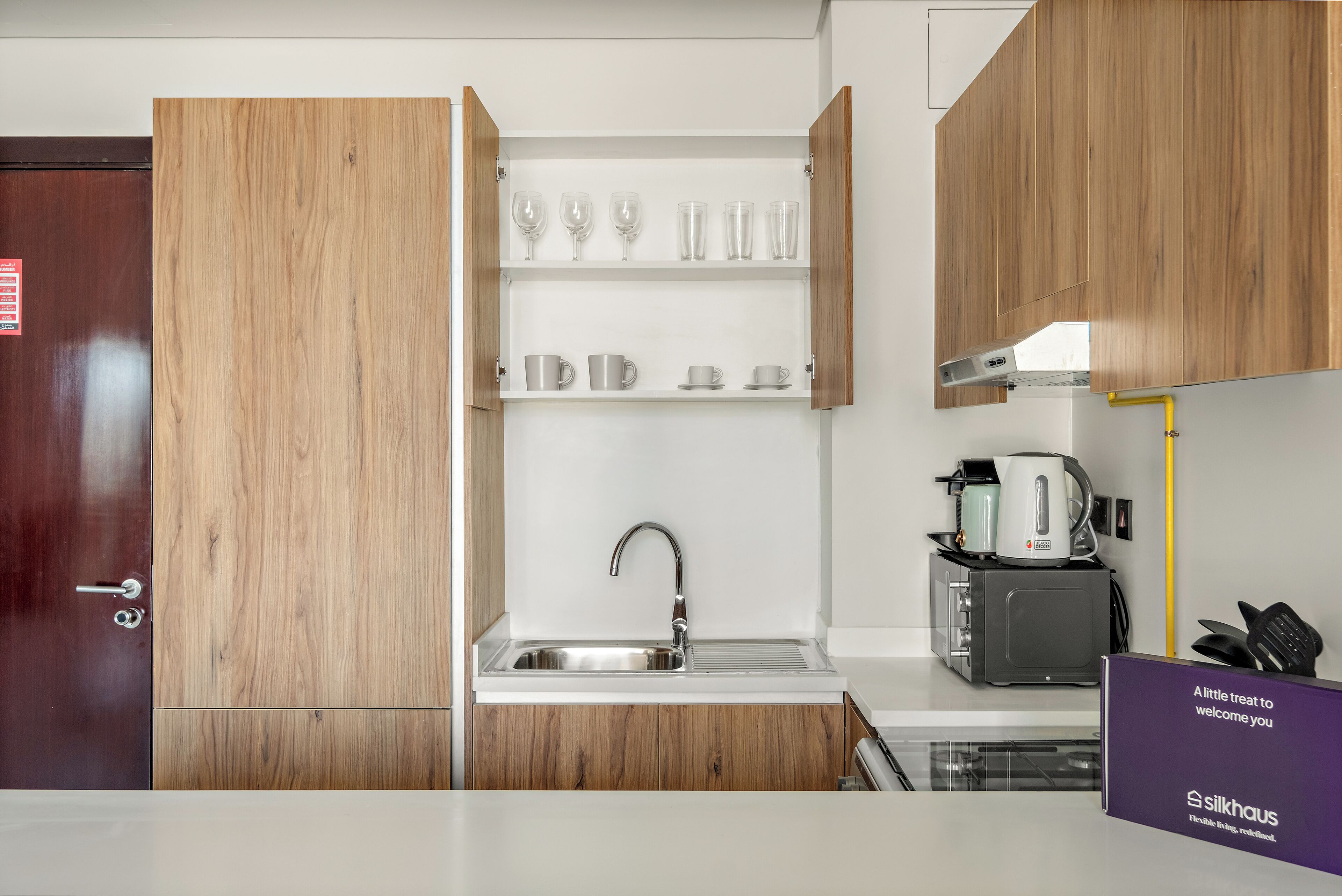 Cozinha moderna com armários de madeira, uma pia de aço inoxidável e uma máquina de café.
