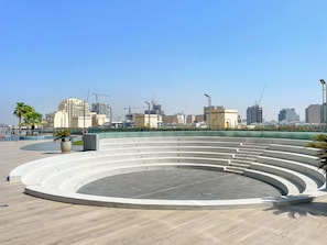 A circular outdoor seating area with a central open space, surrounded by a low wall and a railing.