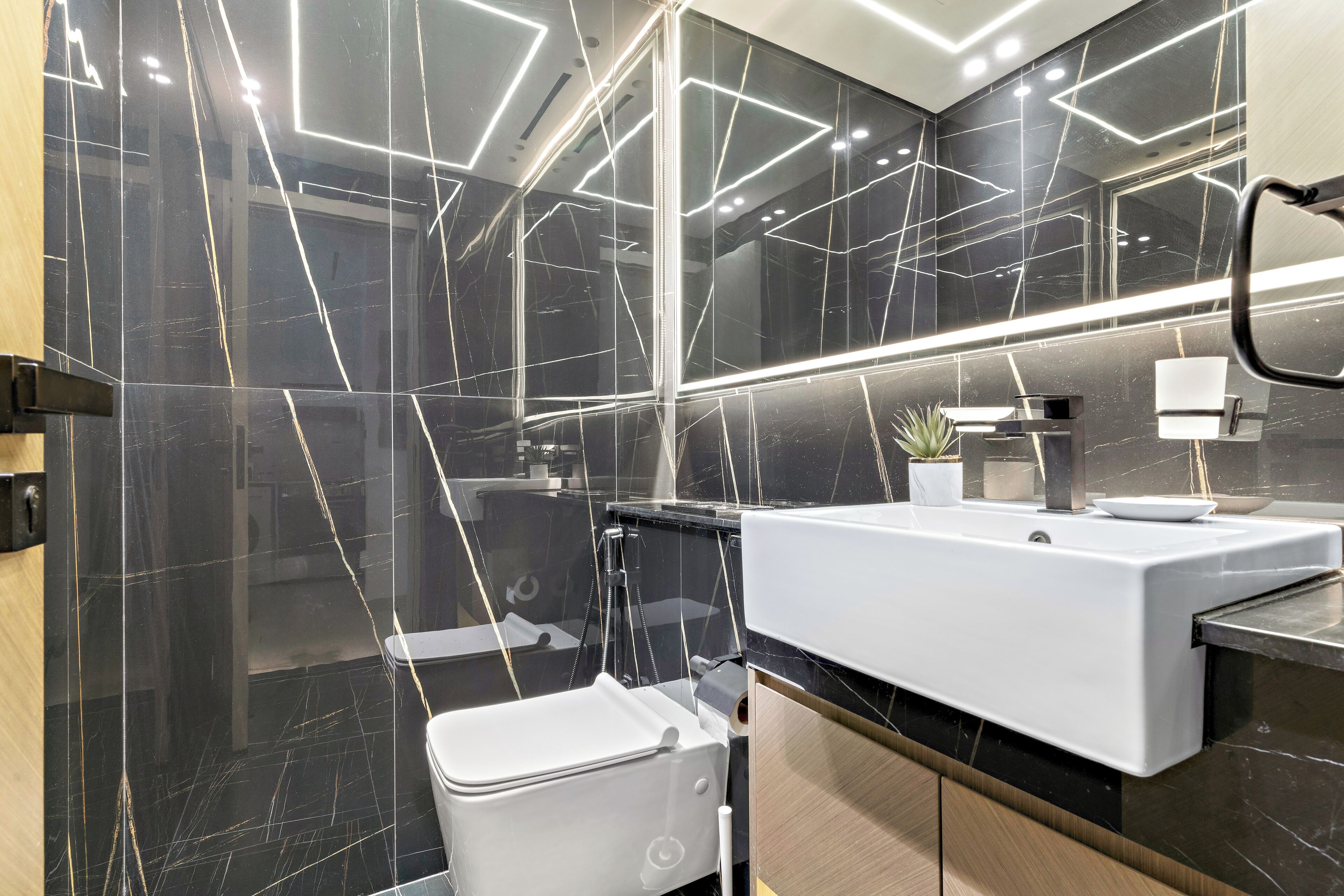 Ein modernes Badezimmer mit einem schwarzen Marmor-Waschtisch, einem weißen Waschbecken und einem Spiegel.