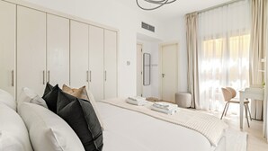 A modern bedroom with a large bed, a desk, and a chair. - Silkhaus Springs 7 (Dubai)