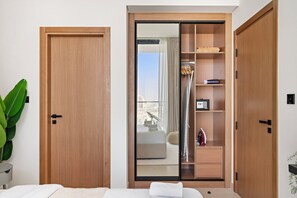 A hotel room with a wooden wardrobe, a sliding glass door leading to a balcony, and a bed with a white comforter.