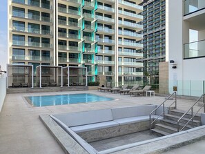 A modern hotel with a rooftop pool area, including lounge chairs and a staircase leading to the upper floors.