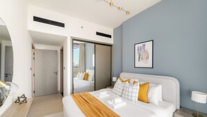 A modern hotel room with a large bed, a bedside table, a nightstand, a mirror, and a framed picture on the wall. - Silkhaus Binghatti Corner (Dubai)