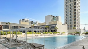 A rooftop pool area with lounge chairs and a view of surrounding buildings. - Silkhaus Binghatti Corner (Dubai)