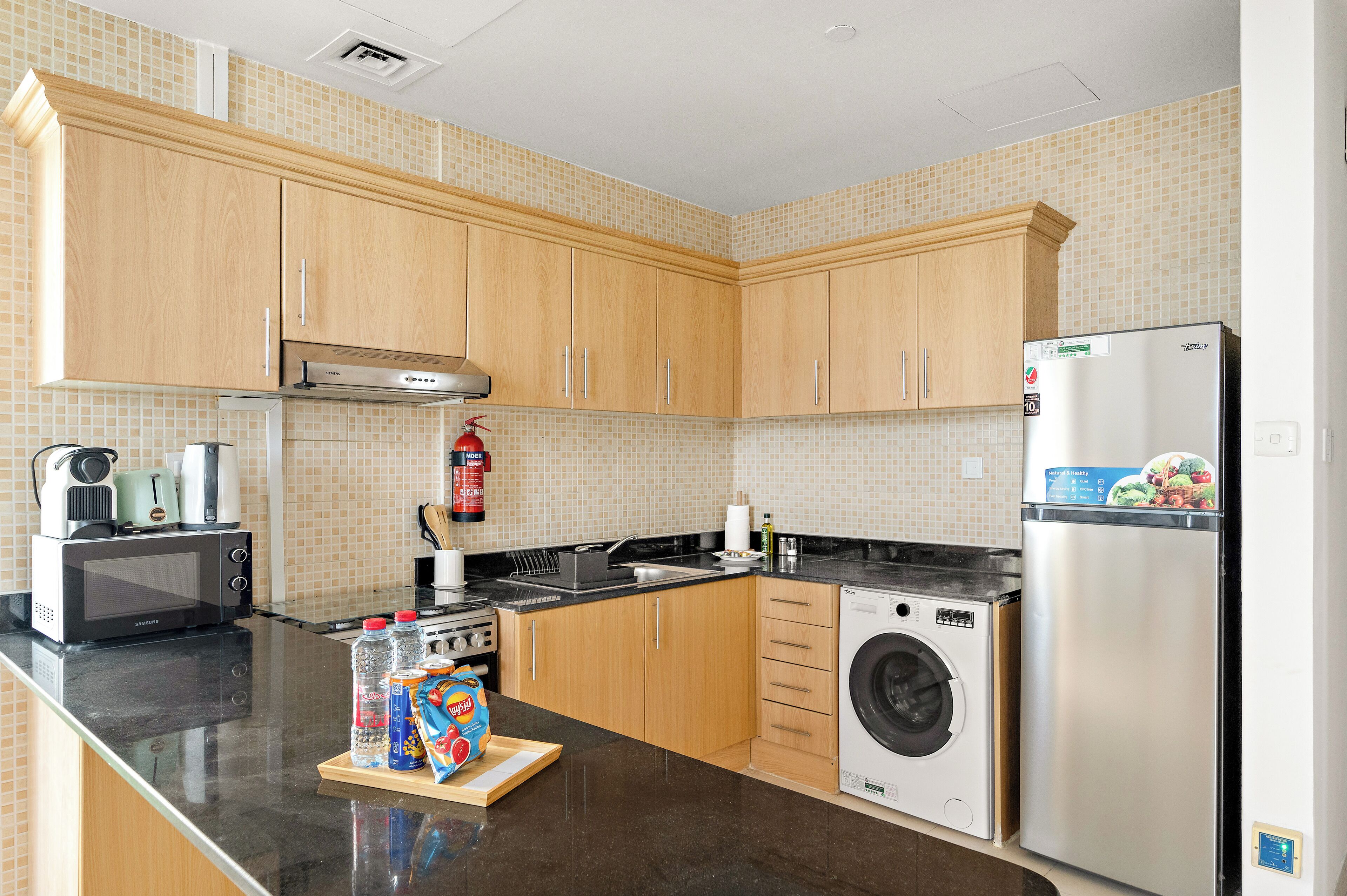 A kitchen with wooden cabinets, a microwave, a washing machine, and a refrigerator.