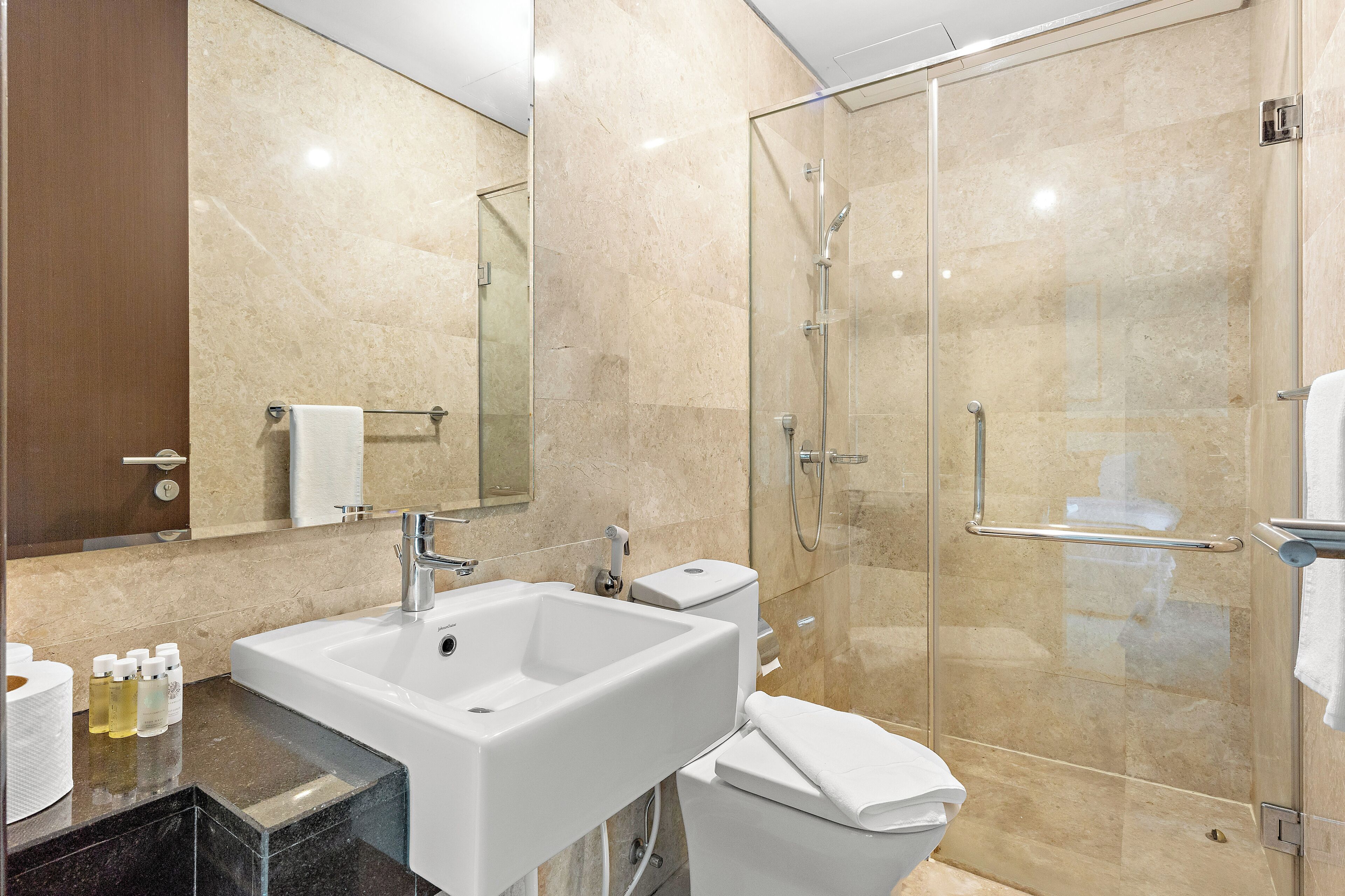 A modern bathroom with a glass-enclosed shower, a white sink, and a toilet.