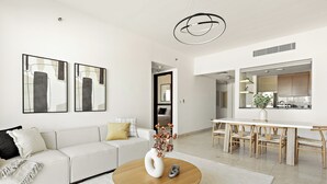 Een moderne woonkamer met een witte bank, een ronde houten salontafel en abstracte wanddecoratie.