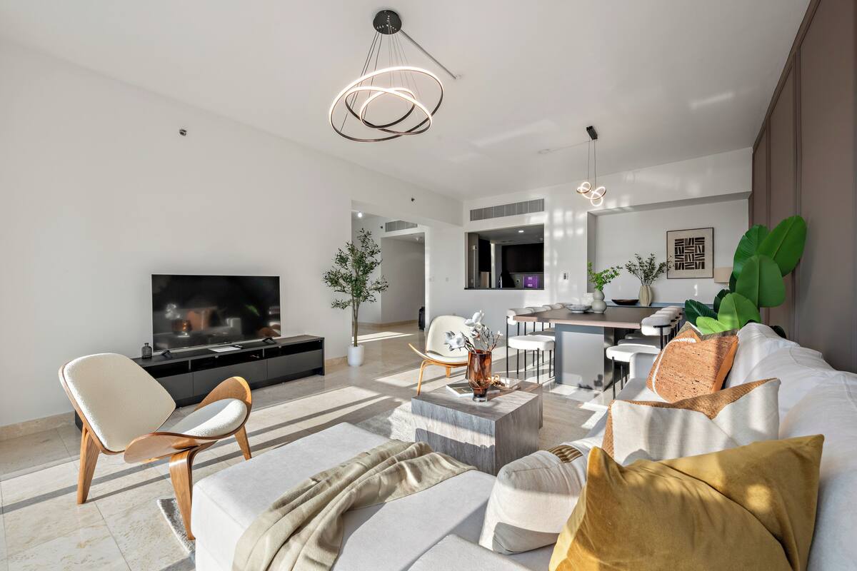 Una sala de estar moderna con sofá, mesa de centro y televisor. Hay un comedor con sillas y una mesa.