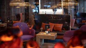 Un espace détente moderne comprenant un canapé, des fauteuils et une table basse en bois, avec des verres et un petit bol.