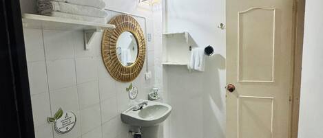 Un bagno con il water, un lavandino e uno specchio. C'è un asciugamano sul water e un portasciugamani sulla parete.