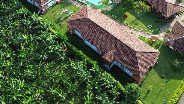 Un resort con diversi edifici, una piscina e una vegetazione rigogliosa.
