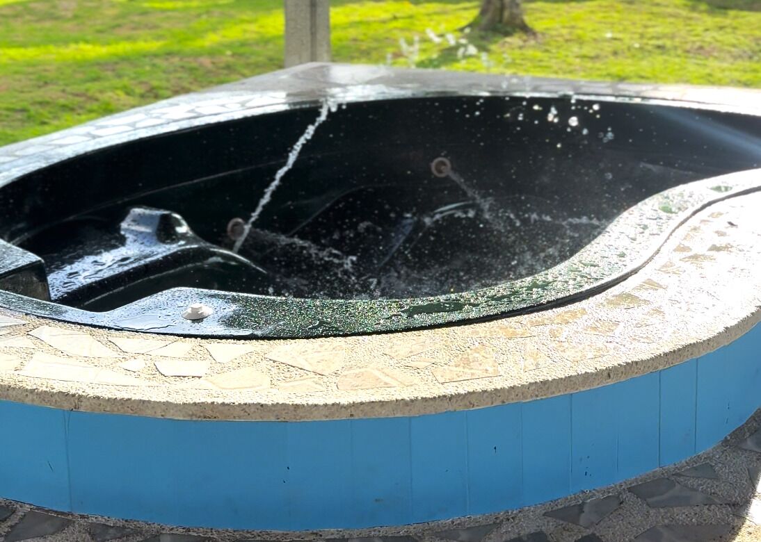 A hot tub with a stone and blue exterior, surrounded by a stone base.
