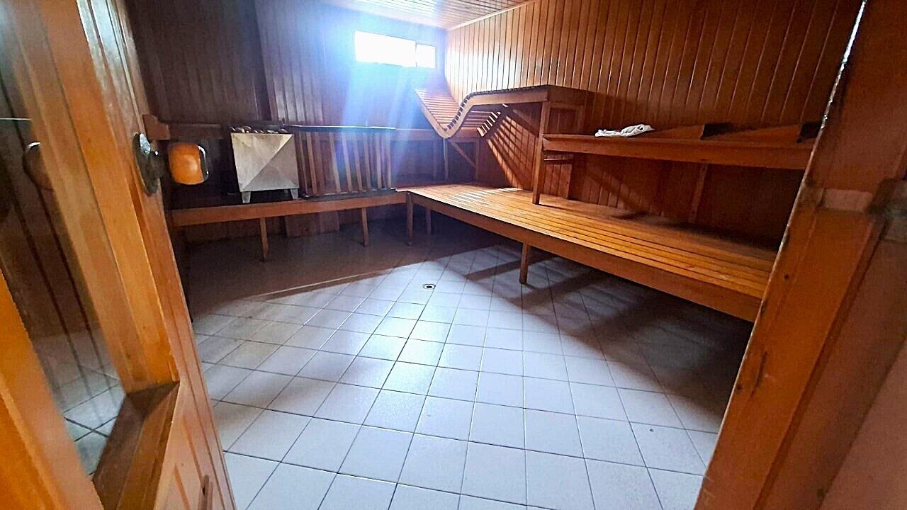 A room with wooden bunk beds, a tiled floor, and a window allowing natural light.