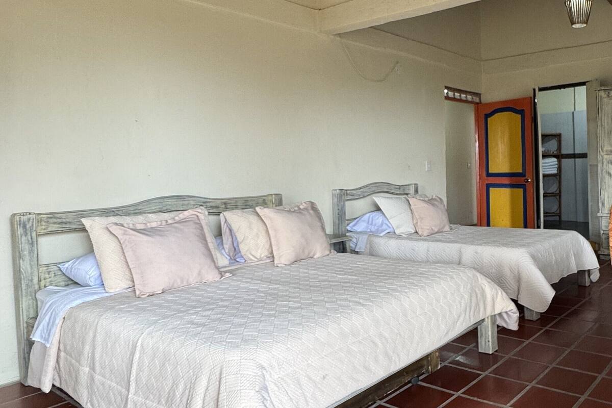 A room with two beds, each with a wooden headboard, and a tiled floor.