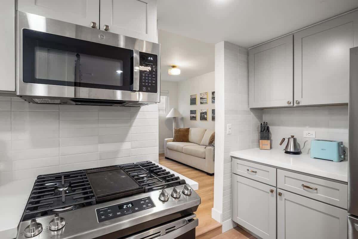 Una cocina moderna con electrodomésticos de acero inoxidable, armarios blancos y una isla central.