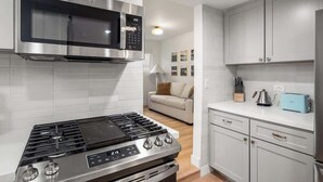 Una cocina moderna con electrodomésticos de acero inoxidable, armarios blancos y una isla central.