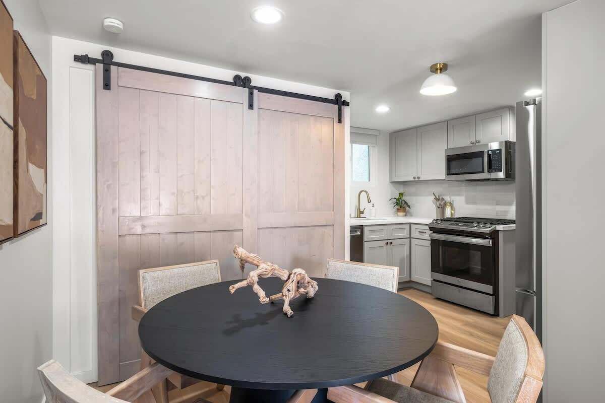 A modern kitchen with a central island, stainless steel appliances, and a sliding barn-style door.