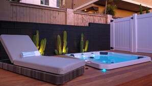 Terraza de madera con una tumbona y un jacuzzi.