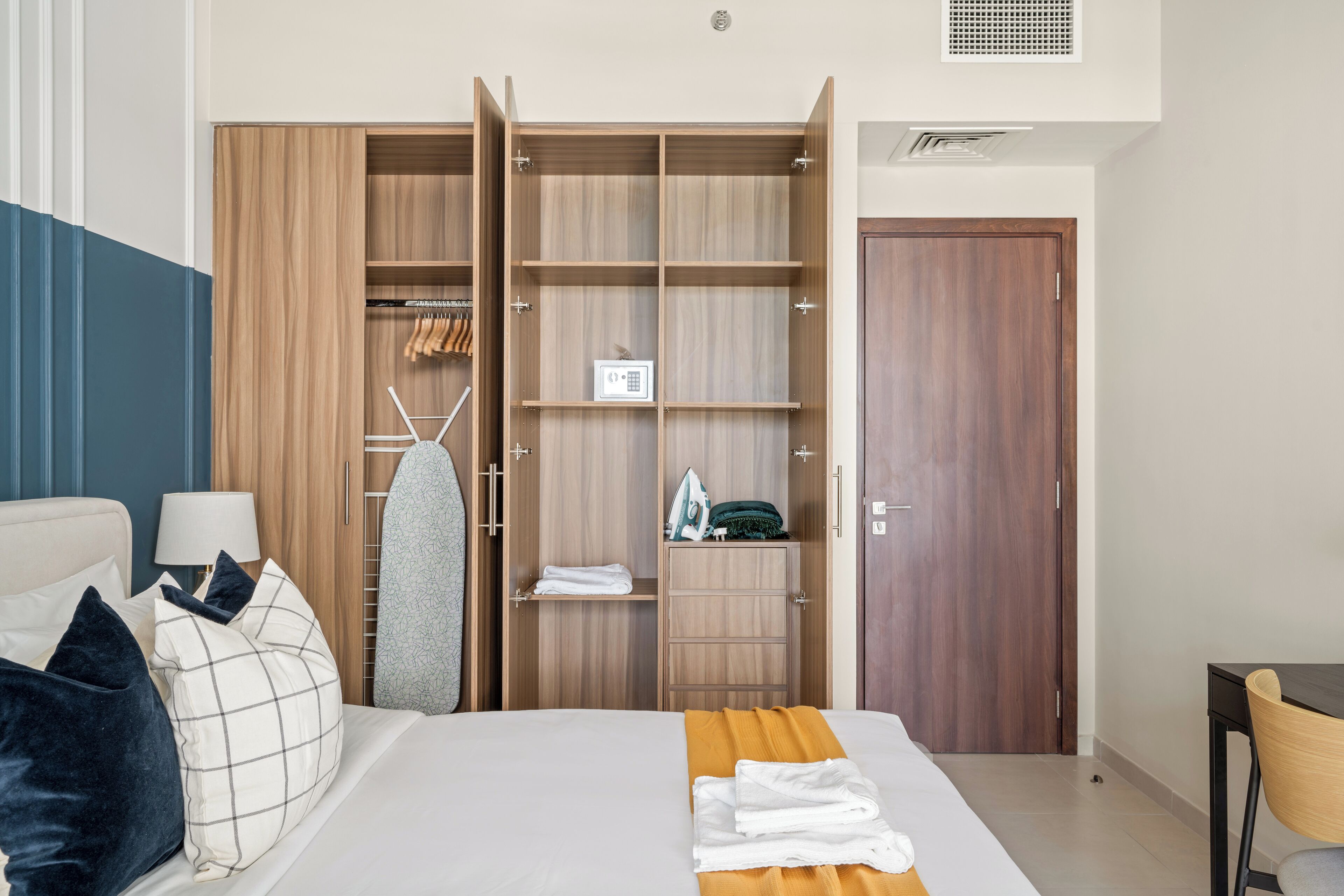 Een hotelkamer met een bed, een kledingkast, een bureau en een stoel.