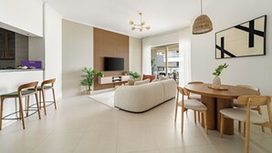 Un salon moderne comprenant un canapé, une table à manger et des chaises, un téléviseur à écran plat et un mur décoratif en bois.