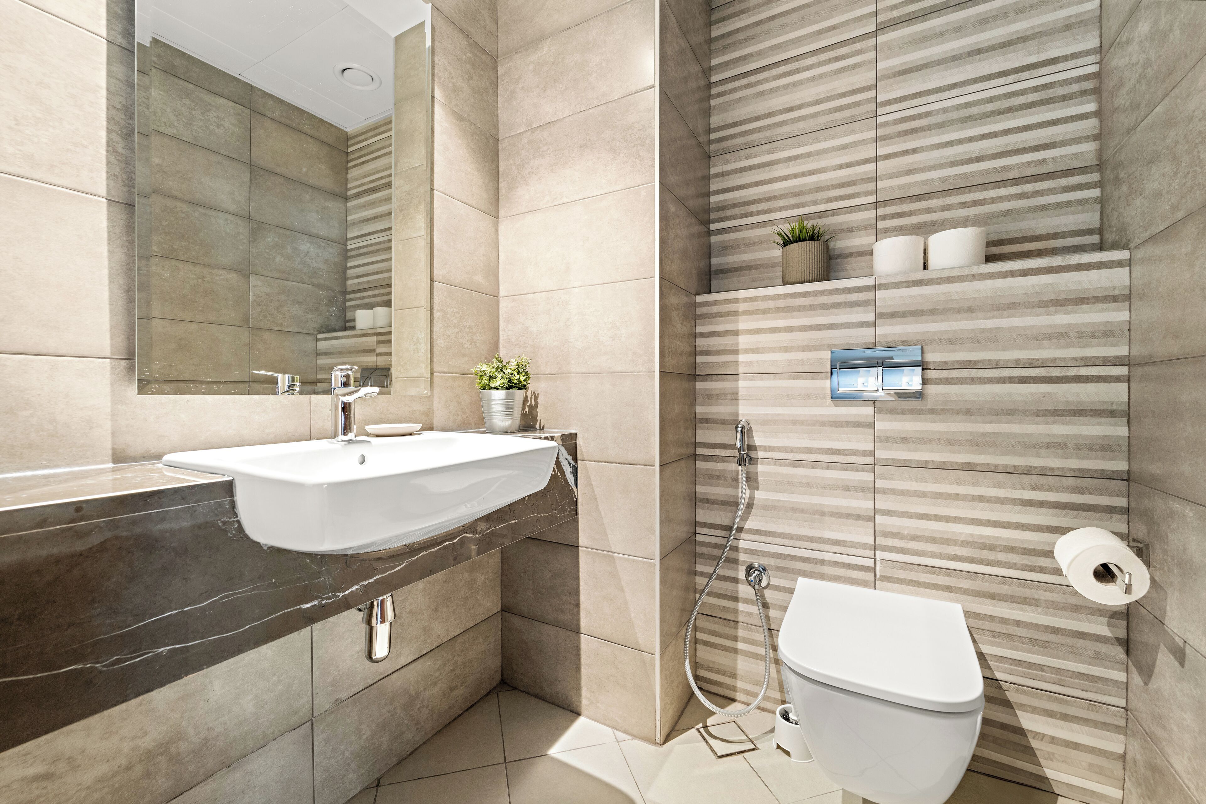 A modern bathroom with a large mirror, a sink, a toilet, and a shower.