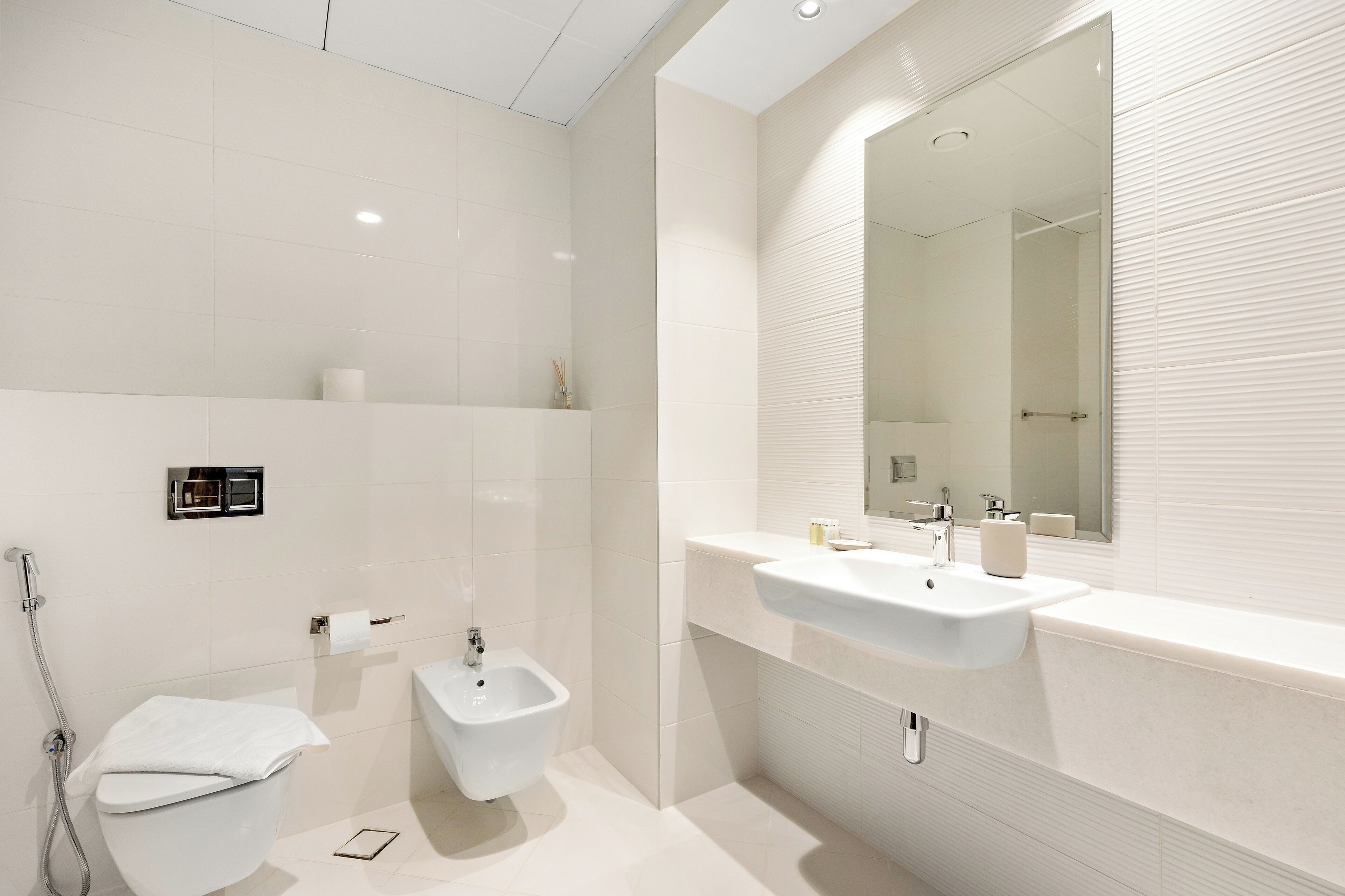 A modern bathroom with a toilet, bidet, and sink.