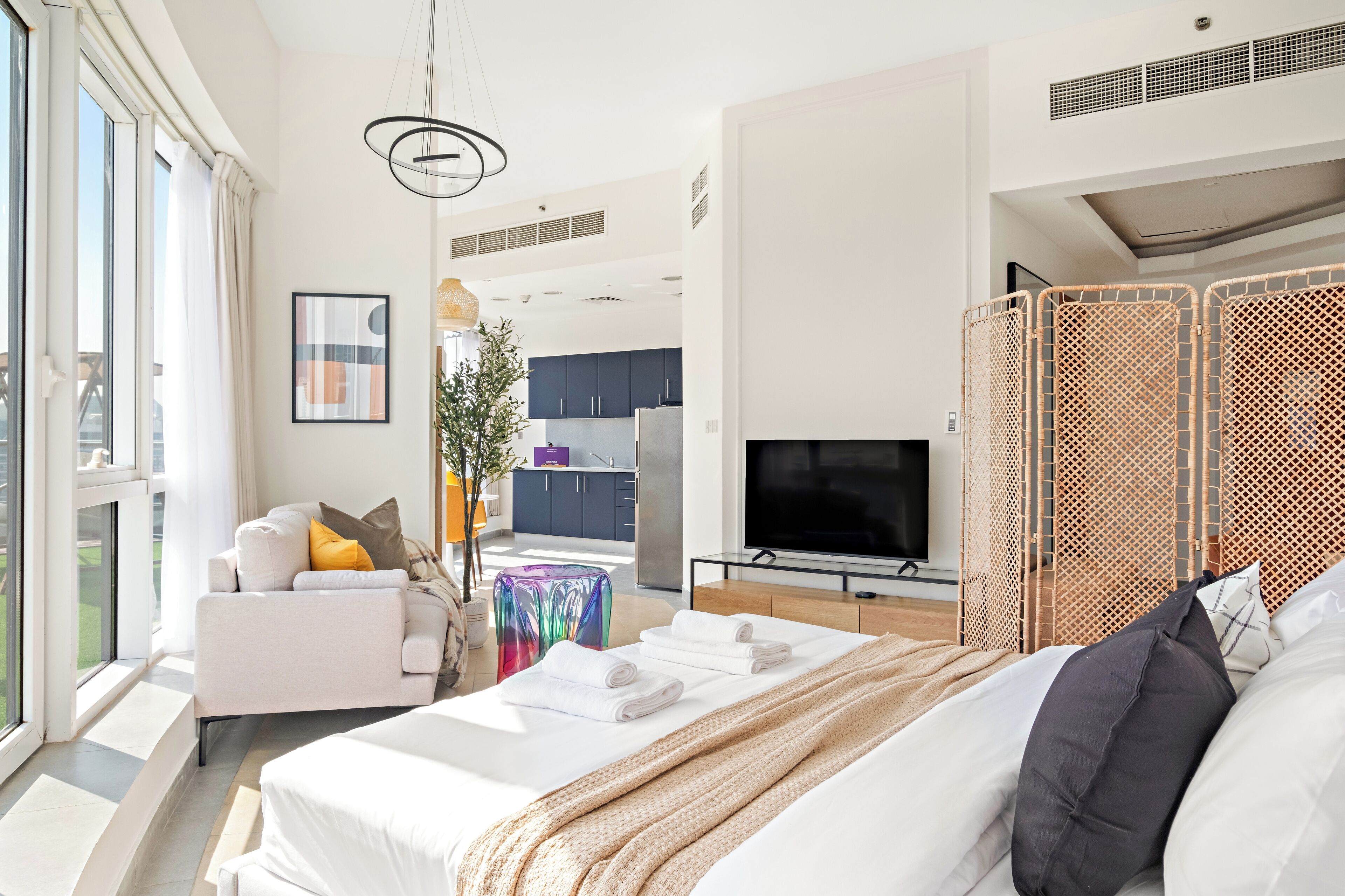 Ein modernes Hotelzimmer mit Bett, Sofa, Fernseher und Balkon.