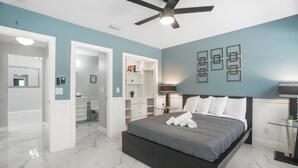 A bedroom with a bed, a ceiling fan, a walk-in closet, and a bathroom.