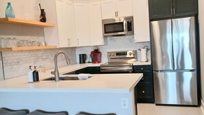 A modern kitchen with white cabinets, stainless steel appliances, and a central island with bar stools. - Bright, quiet, updated condo in Fountain Hills with mountain views! (Fountain Hills)