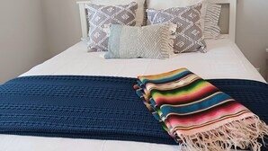 A bed with white bedding, a blue textured blanket, and a colorful striped blanket. - Bright, quiet, updated condo in Fountain Hills with mountain views! (Fountain Hills)