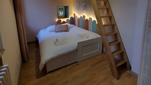 A bedroom with a bunk bed, a wooden ladder, a bedside table, and a hanging light fixture. - Le Cocon, L'Échiquier (Castres)
