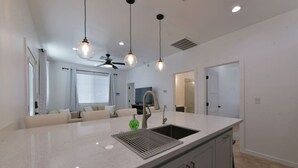 Una cocina moderna con una isla grande, lavavajillas integrado e iluminación colgante.