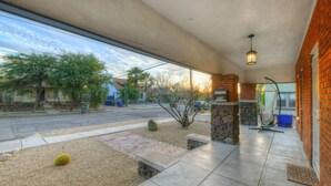 Un patio cubierto con pared de piedra, una silla colgante y vista a la calle.