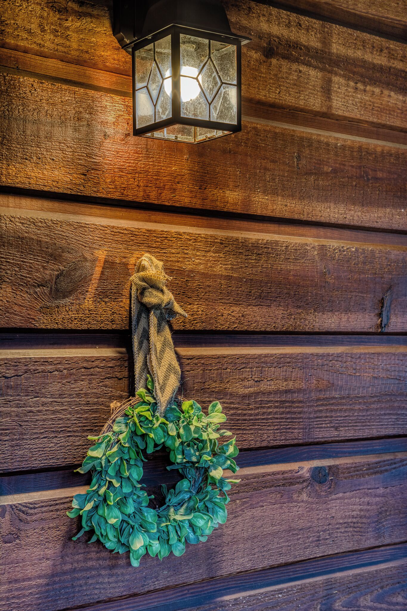 A wooden wall with a hexagonal lantern and a wreath.