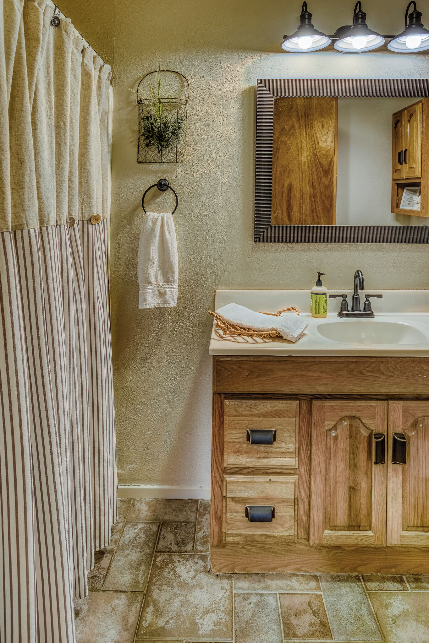 A bathroom with a wooden vanity, a sink, a mirror, and a shower curtain.