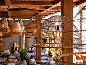 Ein Restaurant mit Korbschwinglampen, Holztischen und -stühlen.
