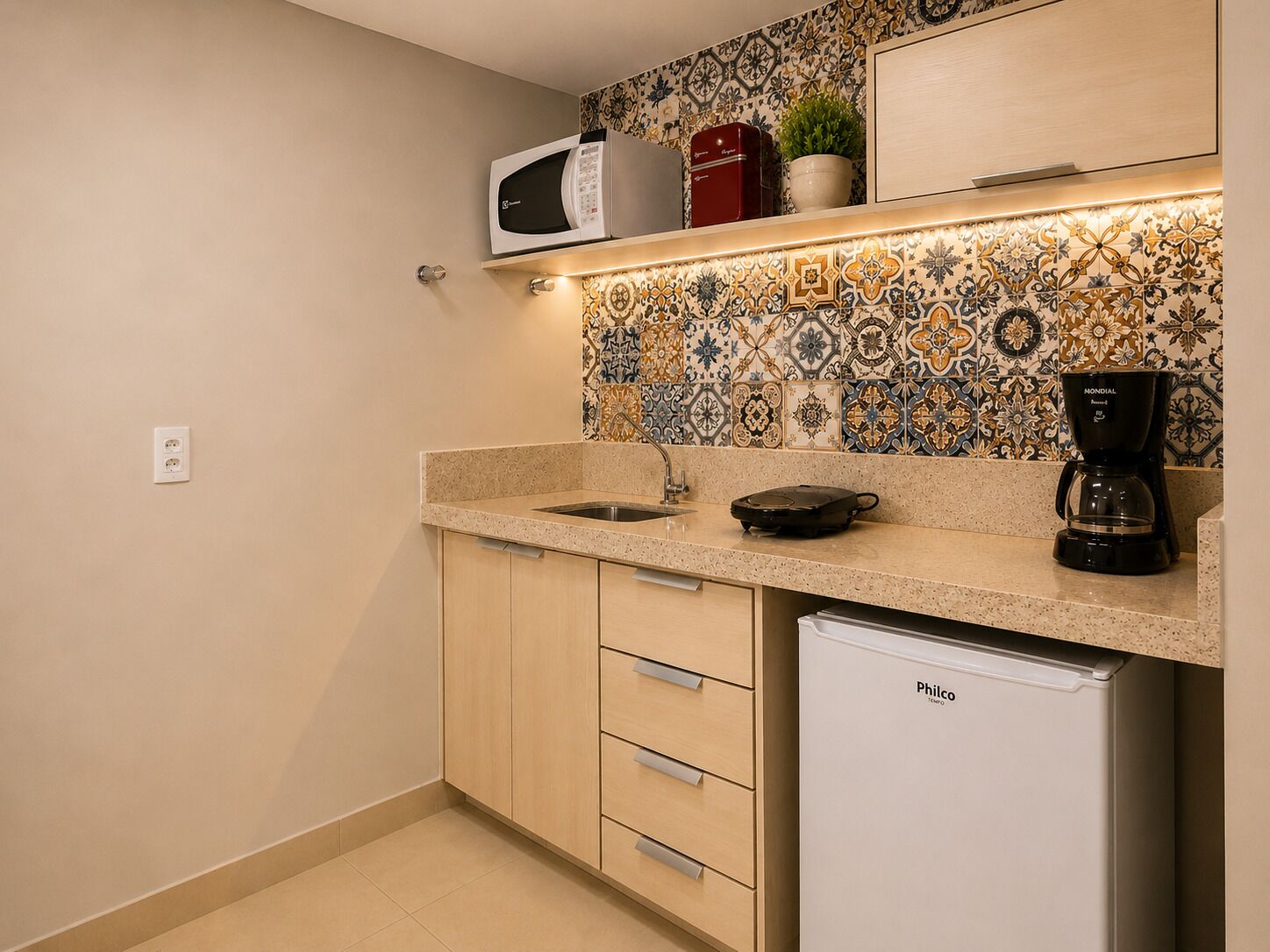 A compact kitchen with a microwave, coffee maker, and a small refrigerator.