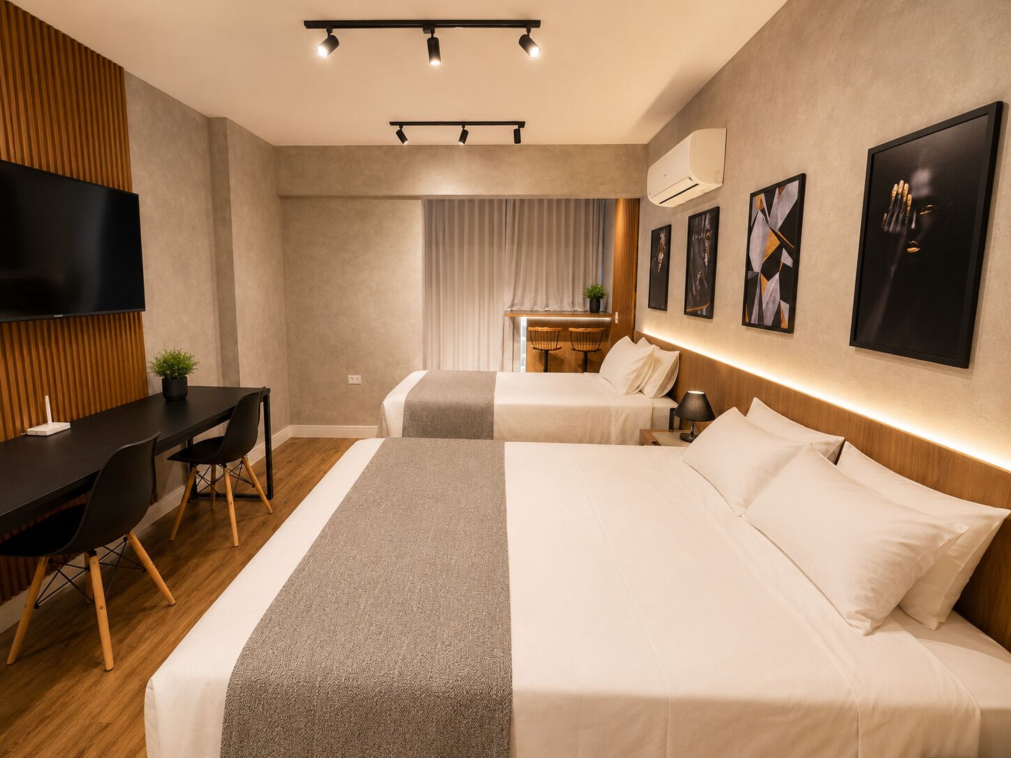 Une chambre d’hôtel avec deux lits, un bureau, un téléviseur à écran plat et des œuvres d’art accrochées aux murs.