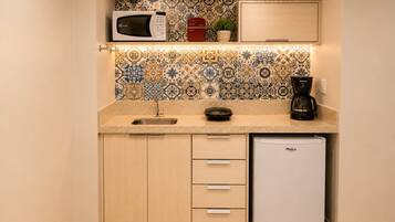 A compact kitchen with a microwave, coffee maker, and a refrigerator.