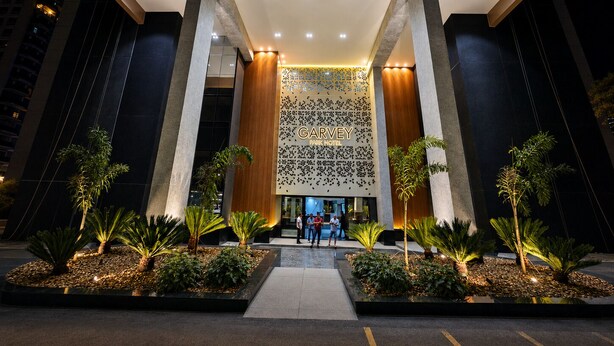 A modern hotel entrance with a prominent sign, large columns, and well-maintained landscaping.