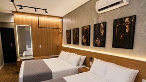 A hotel room with two beds, a large mirror, and artwork on the wall.