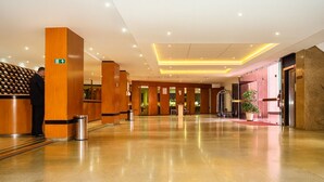 A spacious lobby with a polished floor, wooden reception desk, and a clear exit sign.